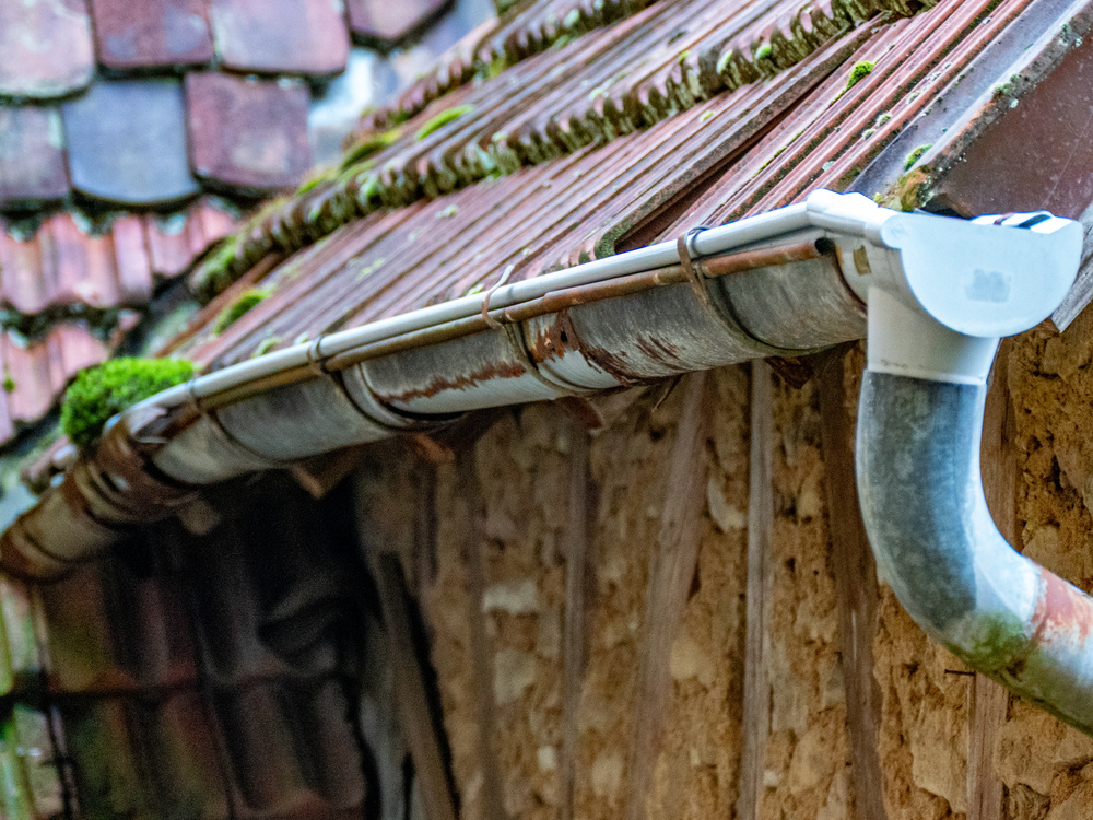 Close-up view of a roof gutter, showing its structure and connection to the roof, with water flowing through it.