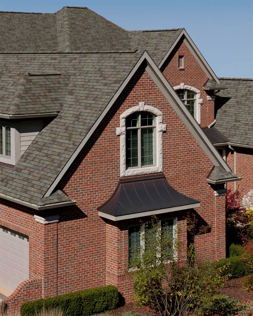 A large brick home featuring a traditional shingled roof, showcasing classic architectural design.