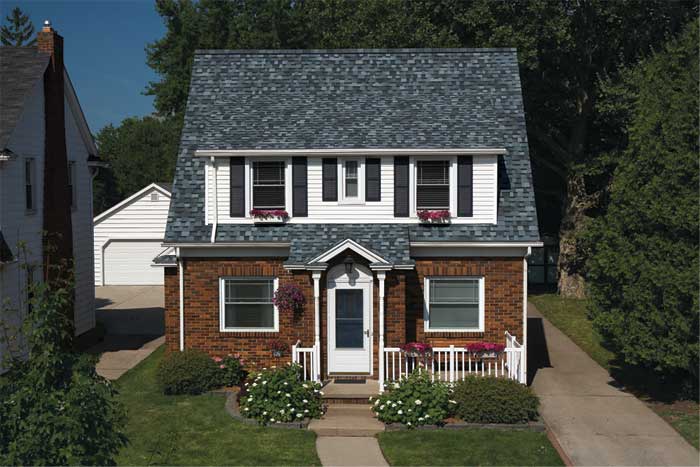 A house featuring a gray roof and white trim, set against a clear blue sky.