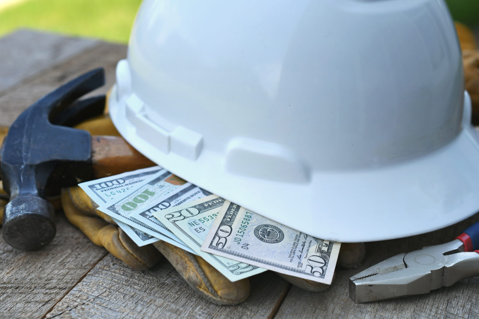 Hard hat with construction tools and cash money - concept for roofing fraud, scam, bribes